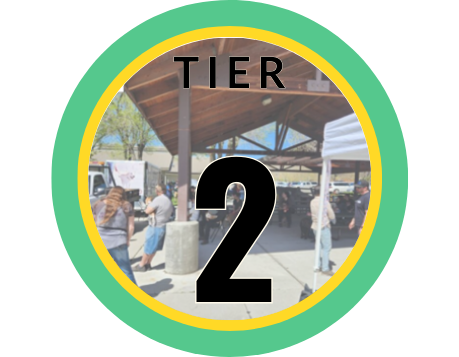 The words Tier 2 overlaid on an image of people in line at a vaccine clinic