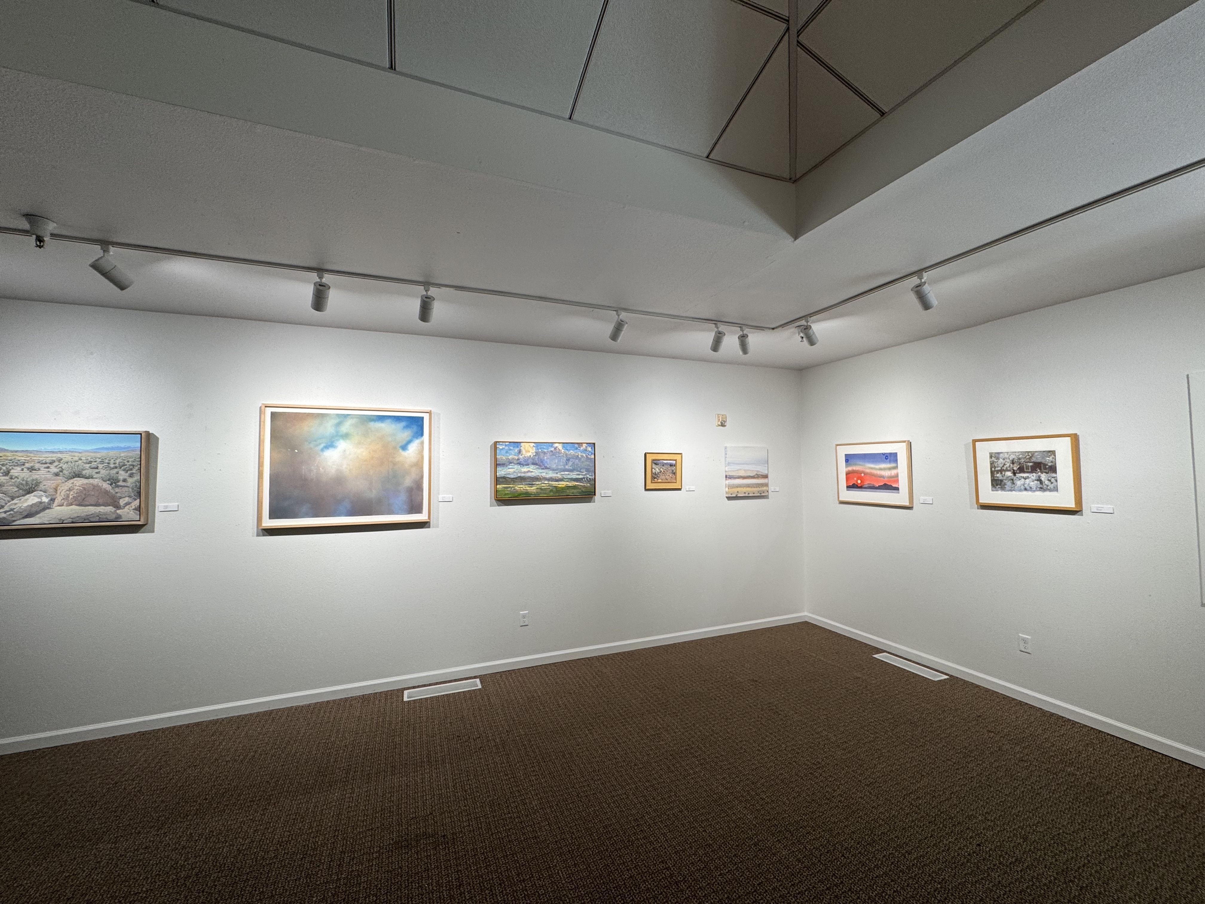 image of white walls with several landscape paintings displayed on them